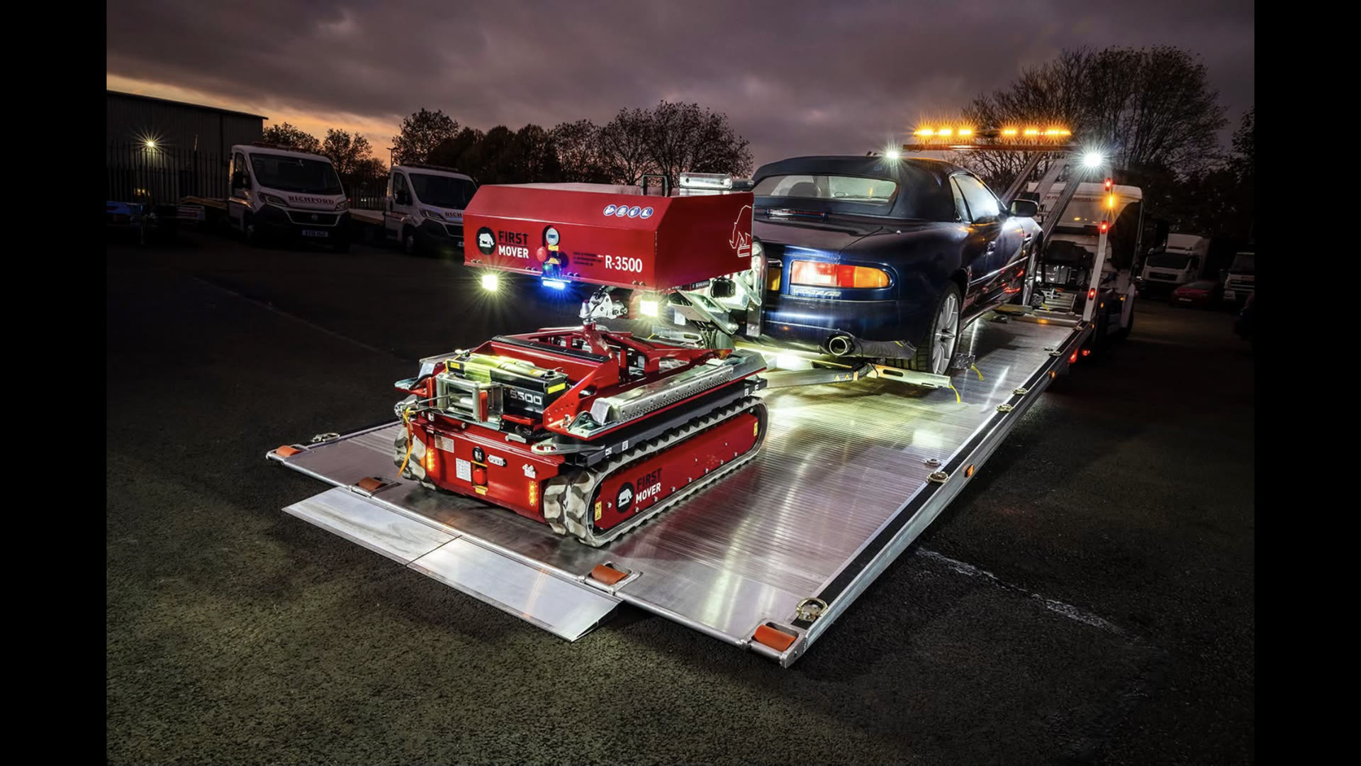 First-Mover R-3500 with a recovered car on a flatbed truck at dusk